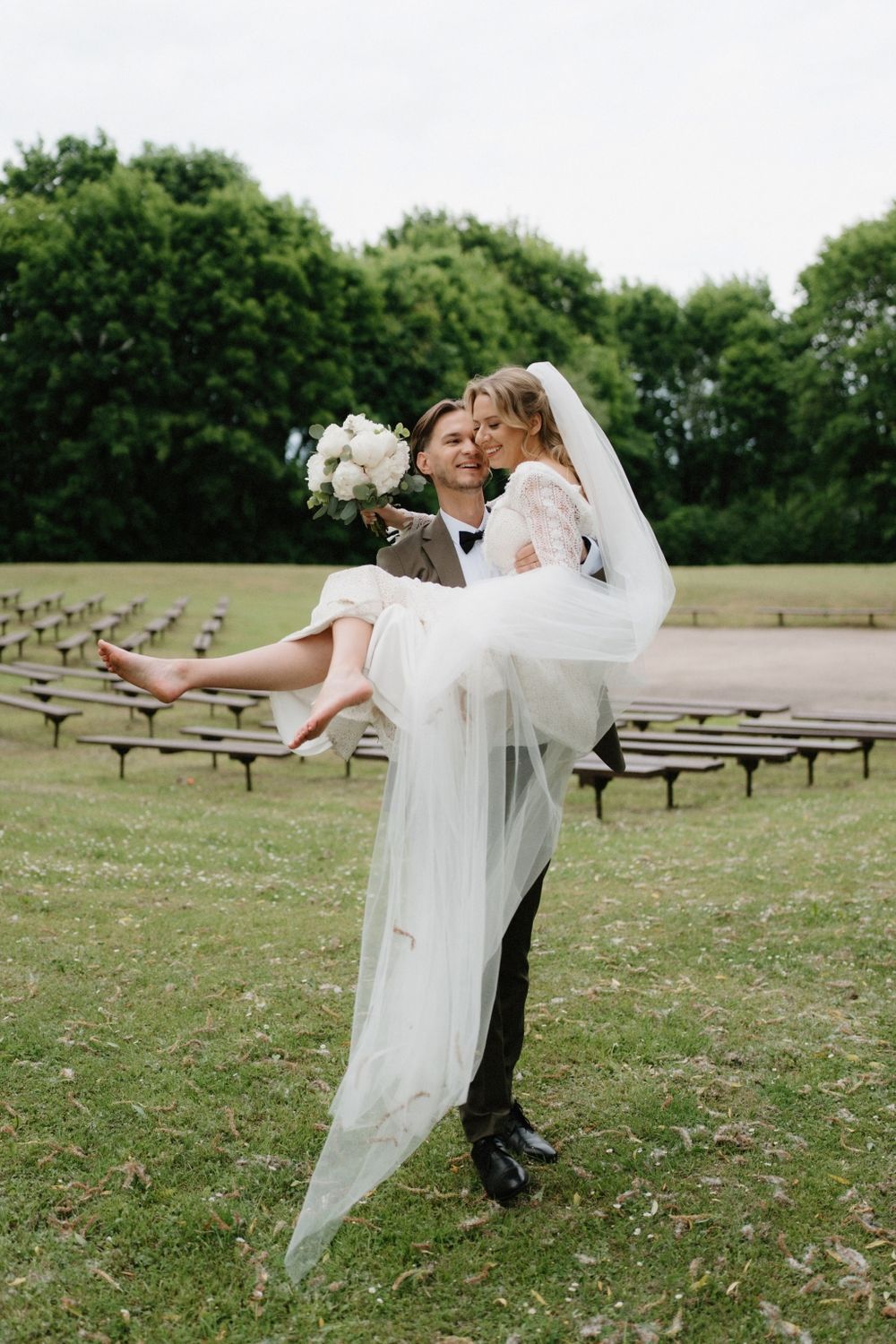 A romantic dance sequence between newlyweds in a grassy outdoor venue with scattered picnic tables.