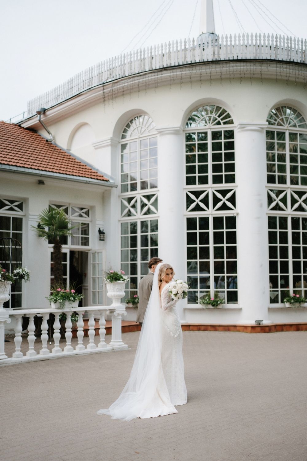 Elegant white conservatory building with arched windows and columns creates a stunning wedding venue backdrop.