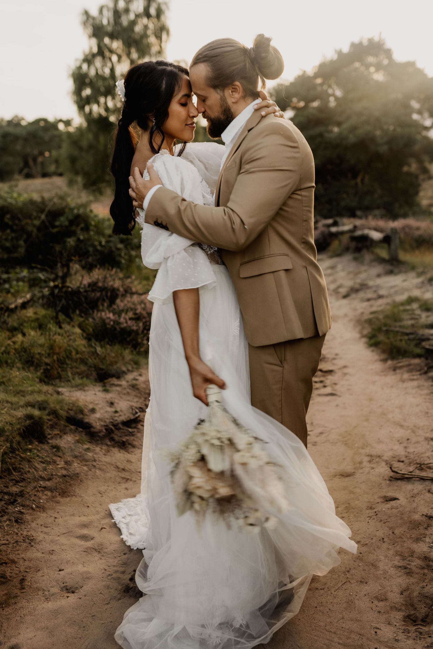 Intimate wedding portrait of a couple embracing on a rustic path at golden hour.