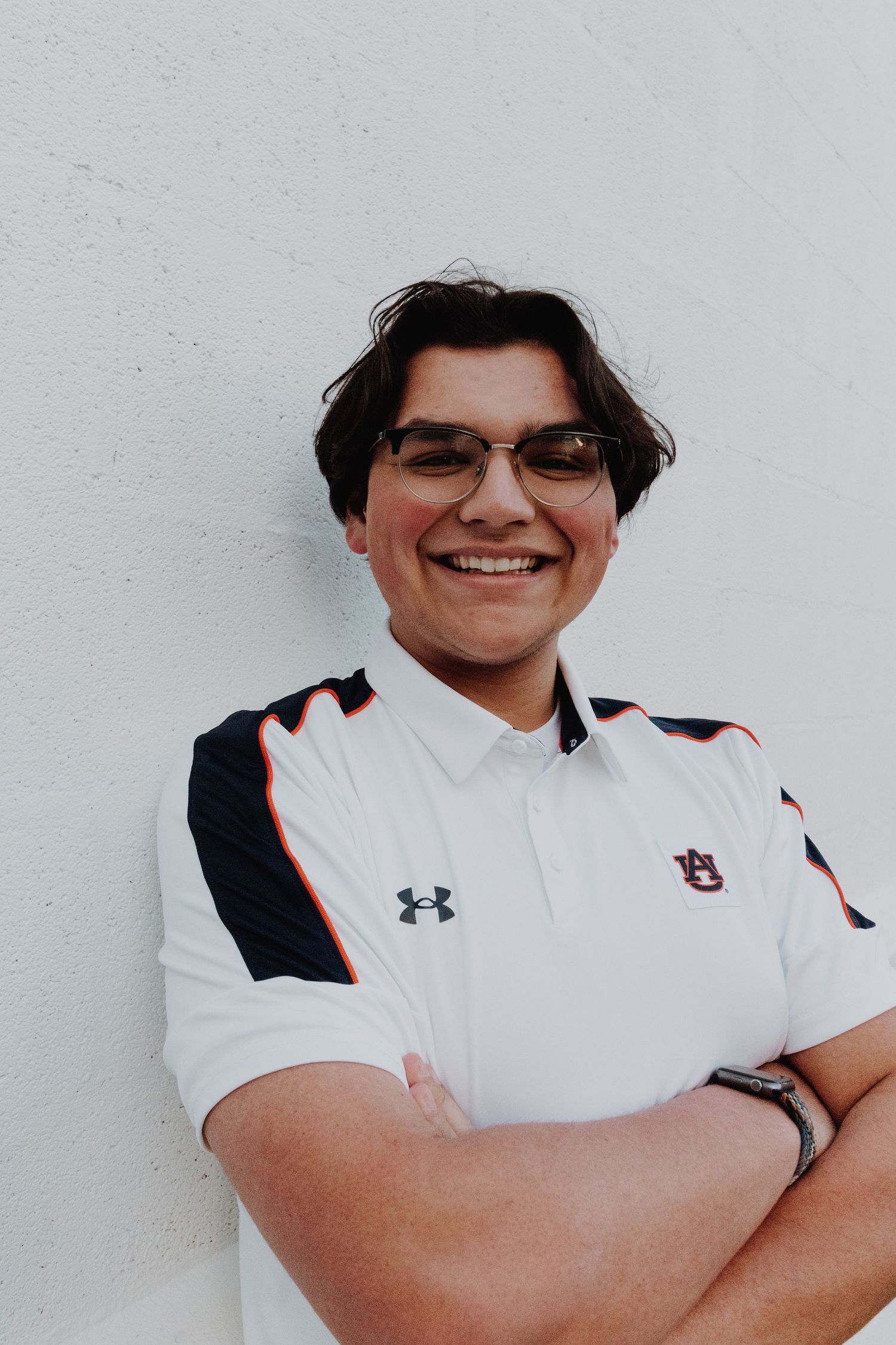 Athletic person in Under Armour uniform smiling confidently against white wall.