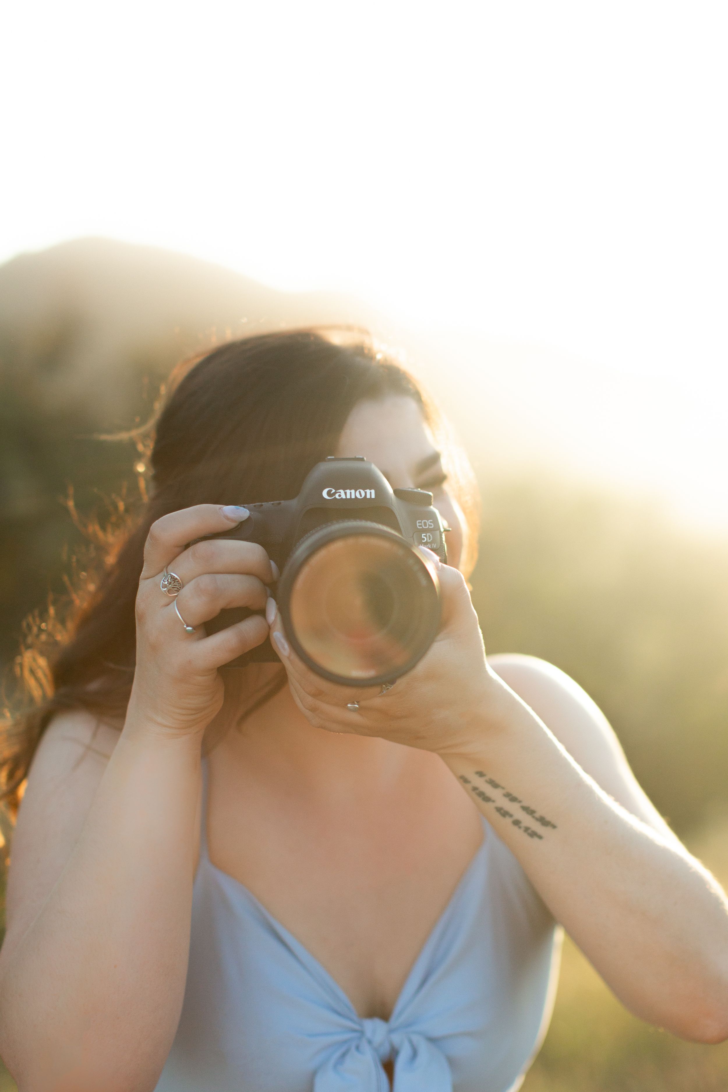 Photographer using Canon camera in soft golden sunlight.