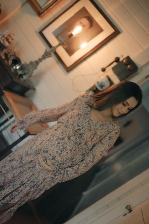 Person wearing floral dress in warmly lit indoor setting.