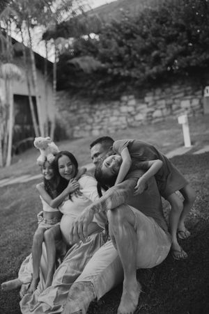 Group playing and laughing together on grass with stuffed animal.