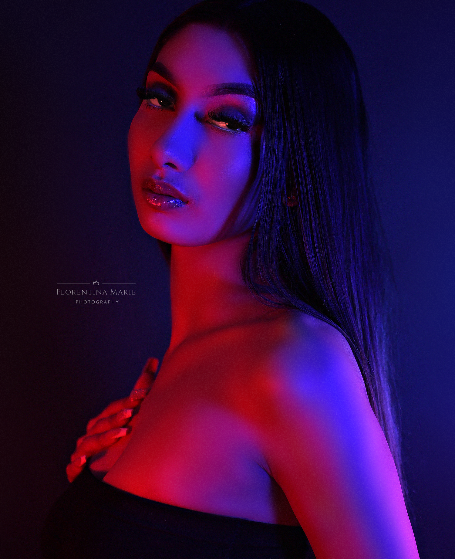 Artistic portrait with red and blue lighting creating a dramatic mood against dark background.
