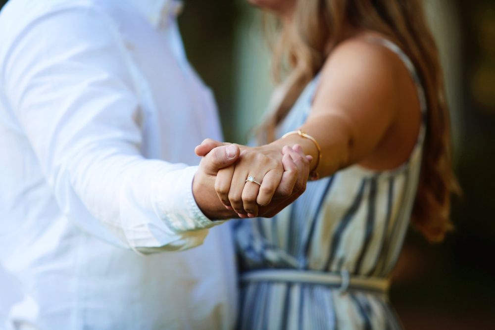 Close-up shot of two hands clasped together in an intimate moment outdoors.