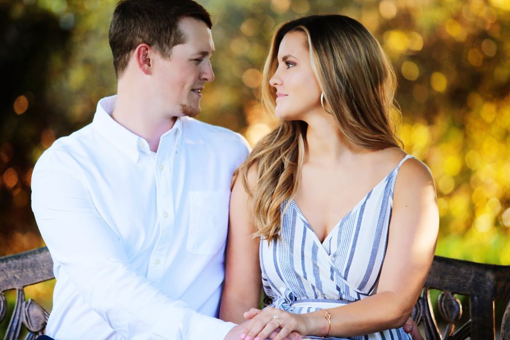 A couple shares a loving gaze while sitting outdoors in golden evening light.