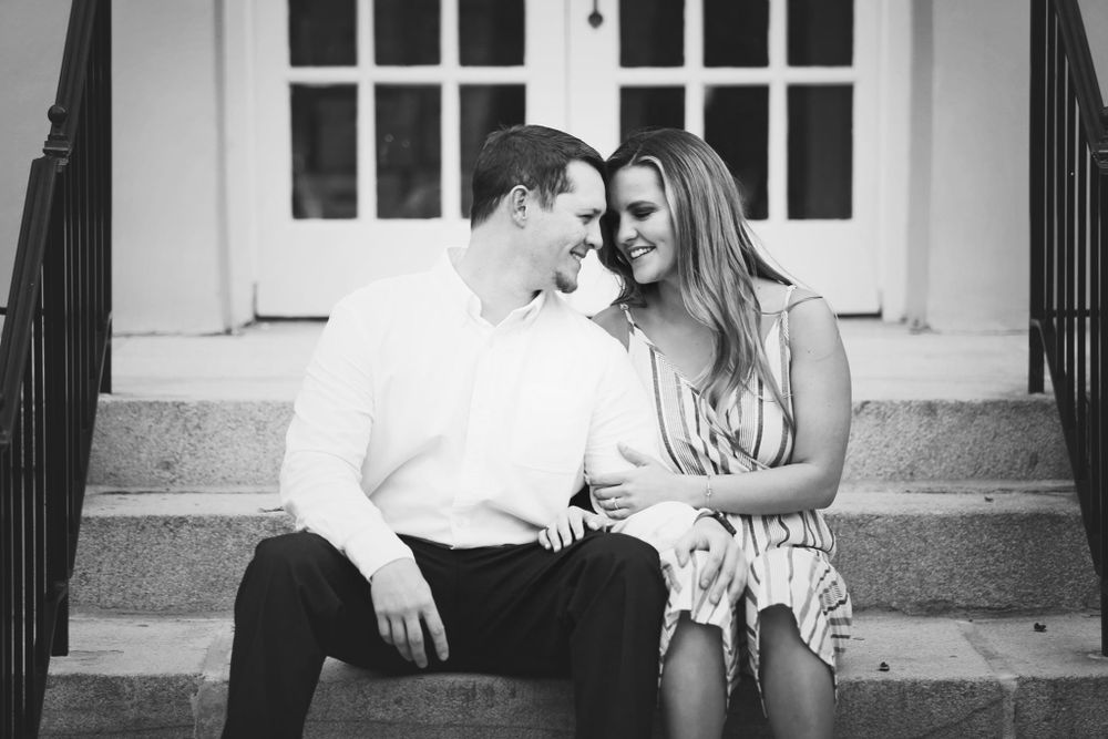 A black and white portrait of a couple sitting close together on stone steps.