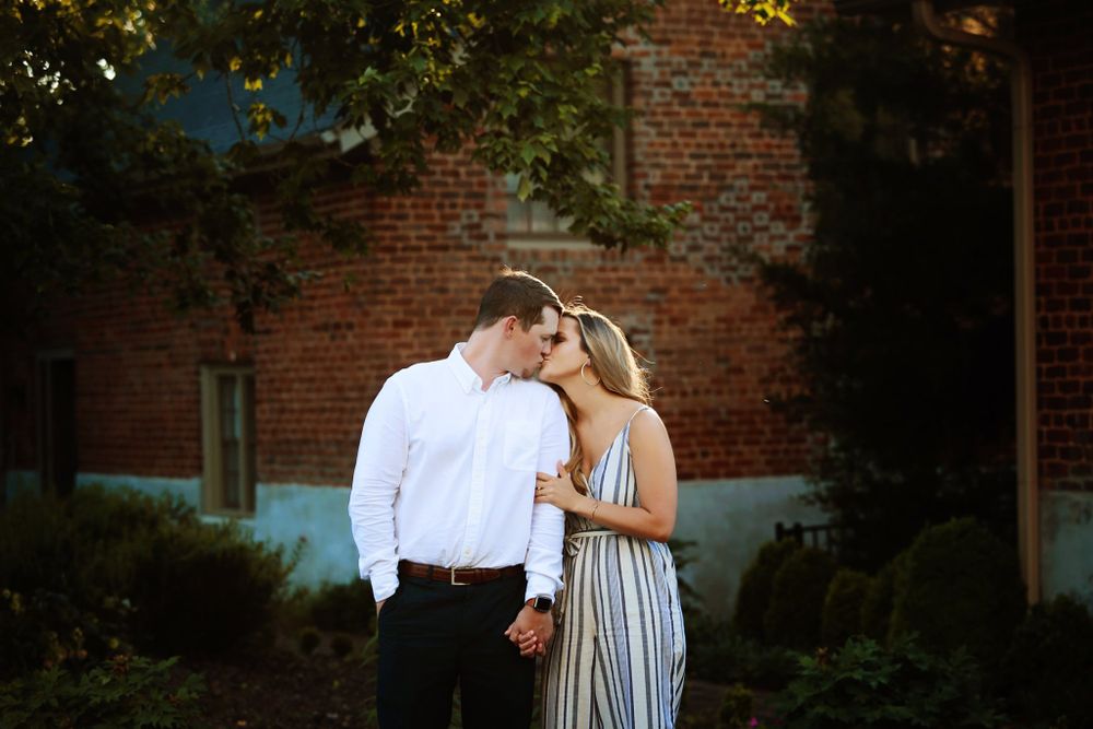 A tender moment between a couple against a brick wall background in an outdoor setting.