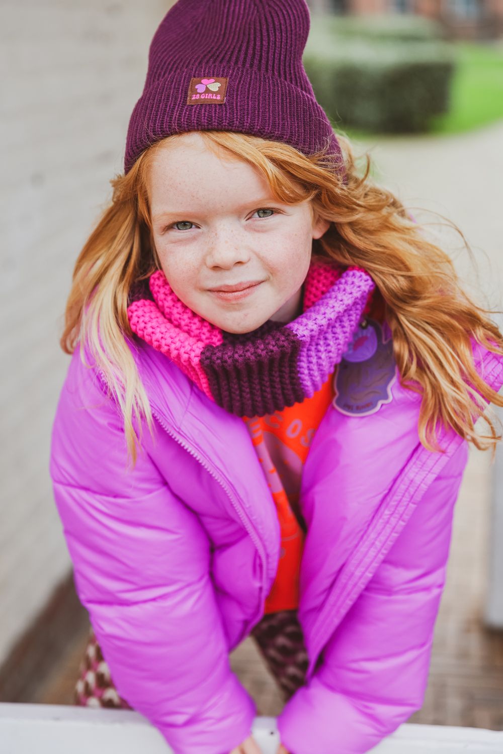 A cheerful winter scene with vibrant purple coat and matching knit accessories.