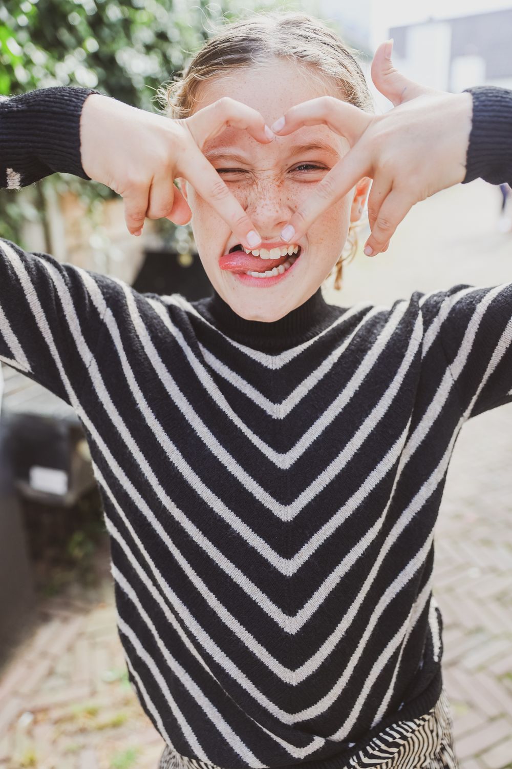 Playful pose in a black and white striped sweater making gestures.