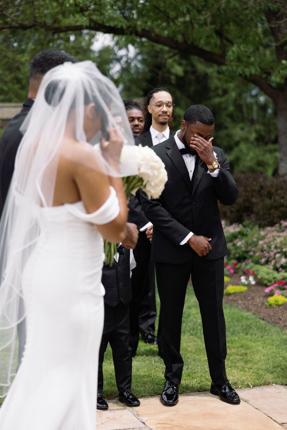 Emotional wedding first look moment captured in outdoor garden setting.