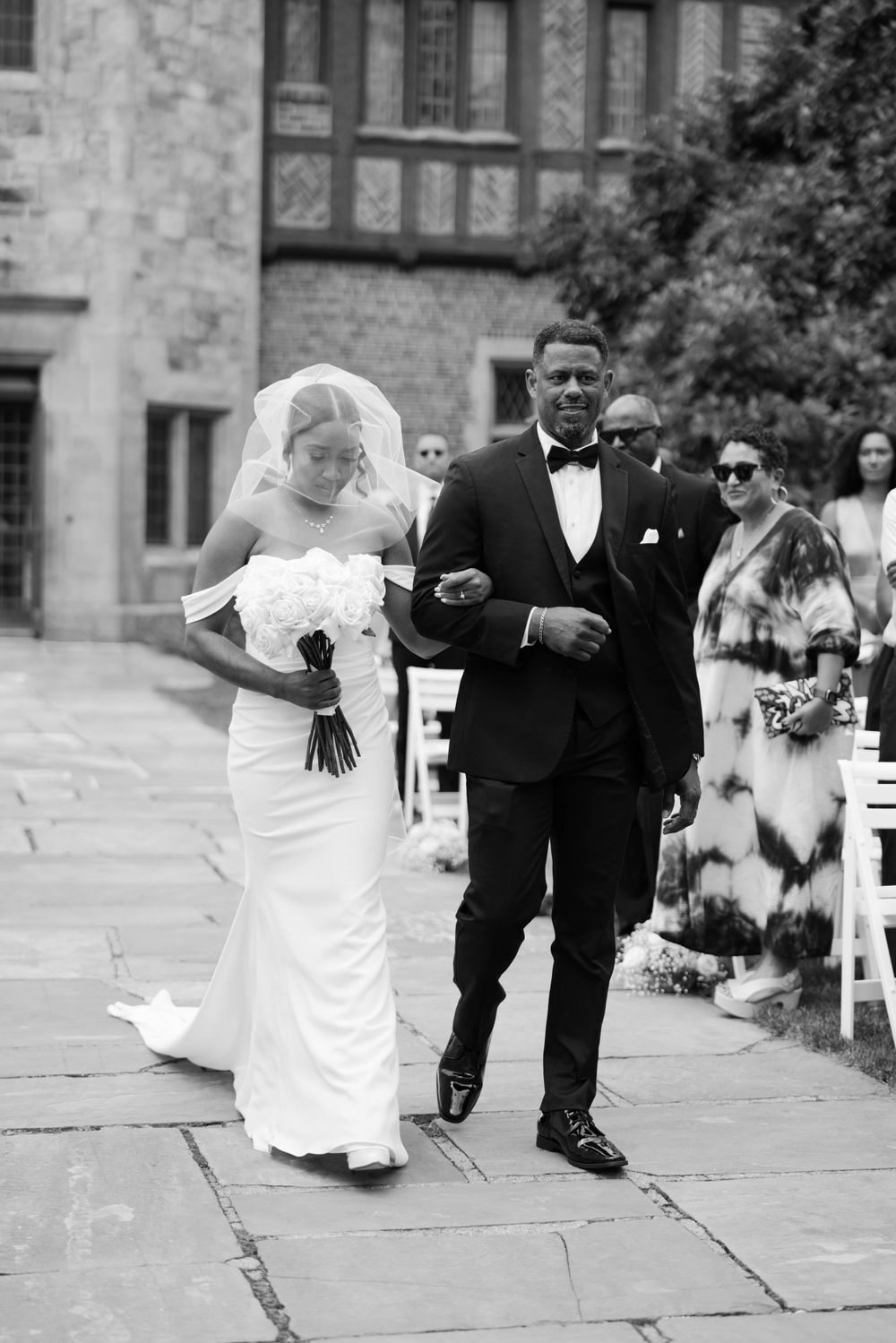 Black and white photo of couple walking down stone path after wedding ceremony.
