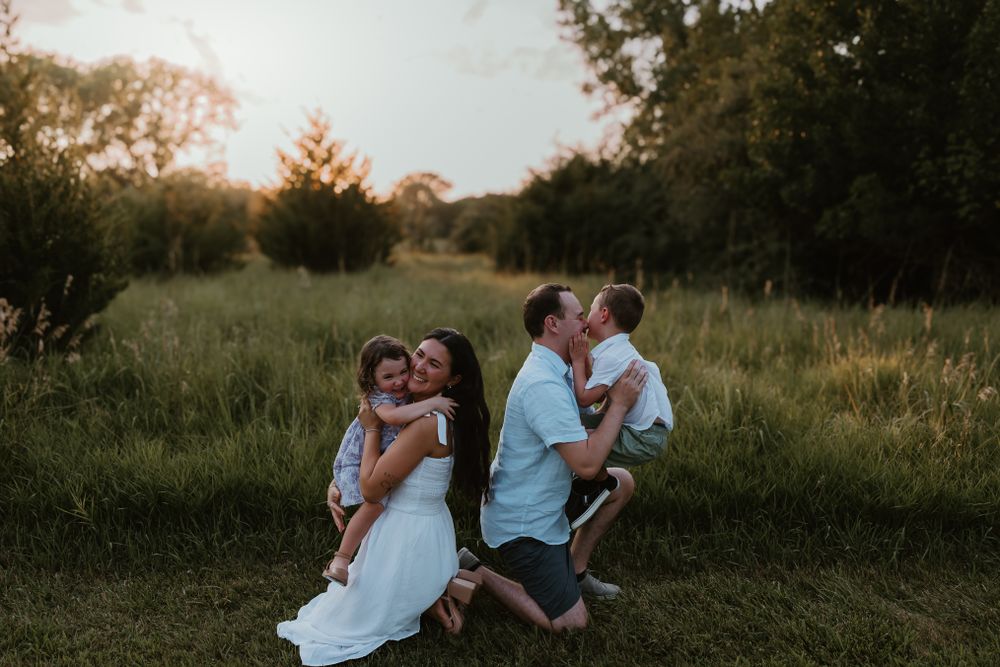 Two couples embrace in a sun-drenched field during golden hour. Colorado Springs Photographer.