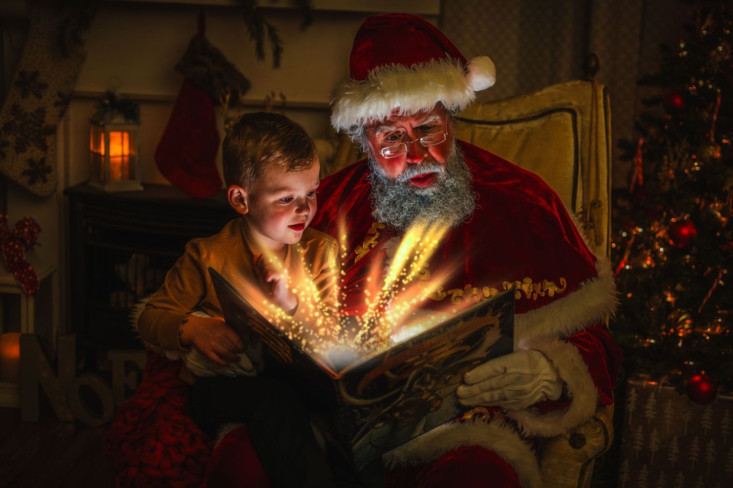 A person in a Santa costume opens a magical glowing book with a child next to a decorated Christmas tree.