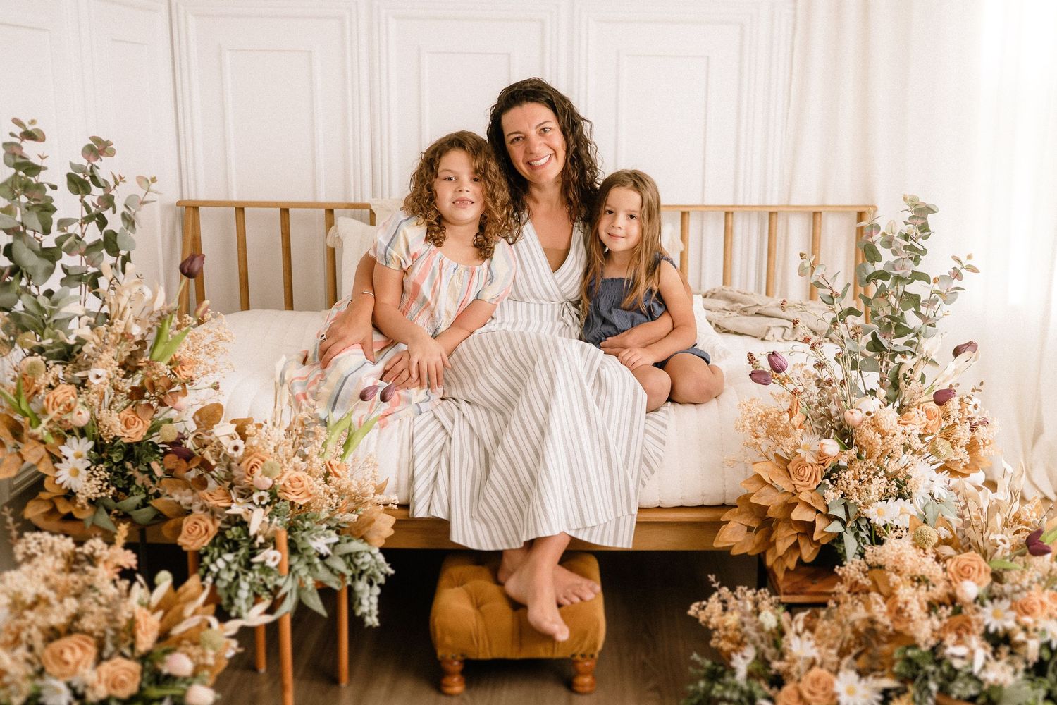 A heartwarming family portrait on a wooden bench surrounded by beautiful peach and cream floral arrangements.