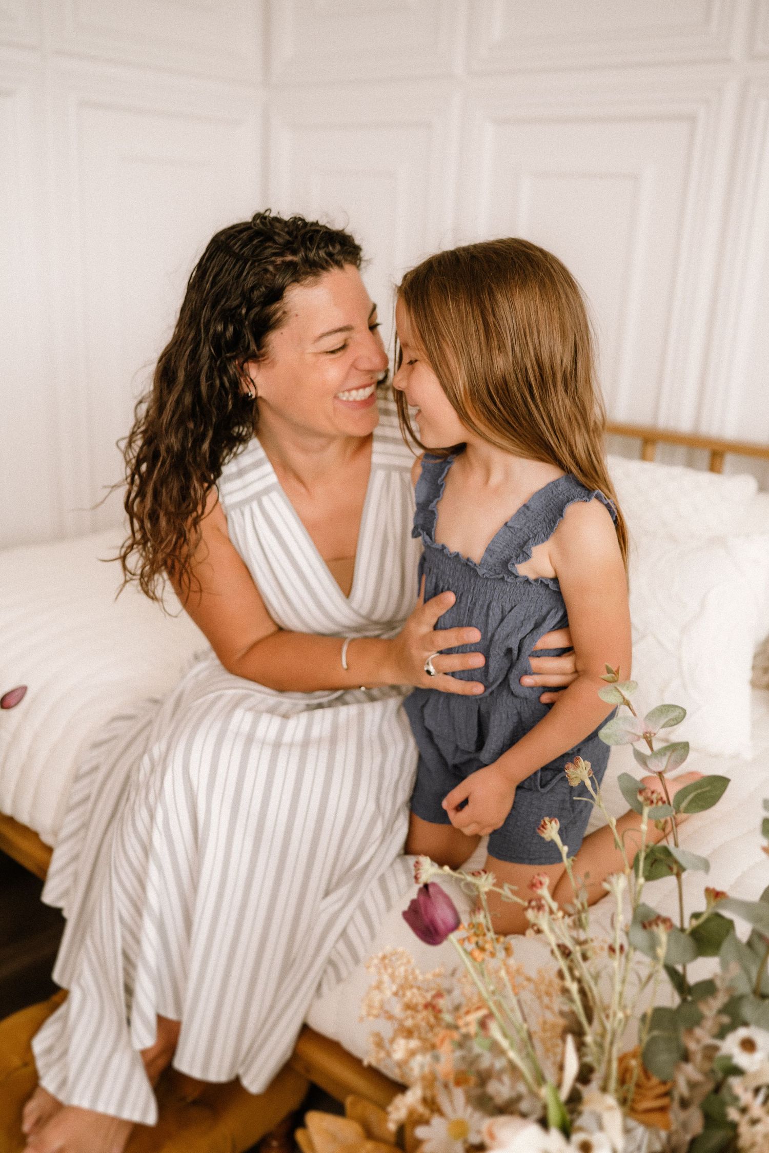 Intimate mother-child portrait with floral decorations and white paneled walls.
