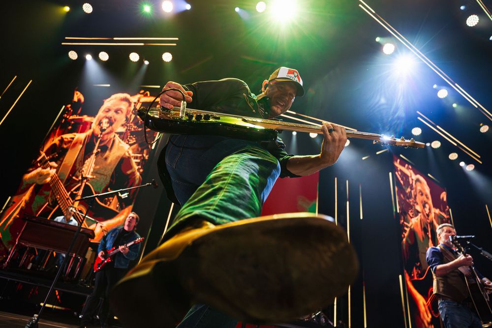 Energetic live concert performance of Christian band Third Day with musicians playing guitar and violin under colorful stage lights.