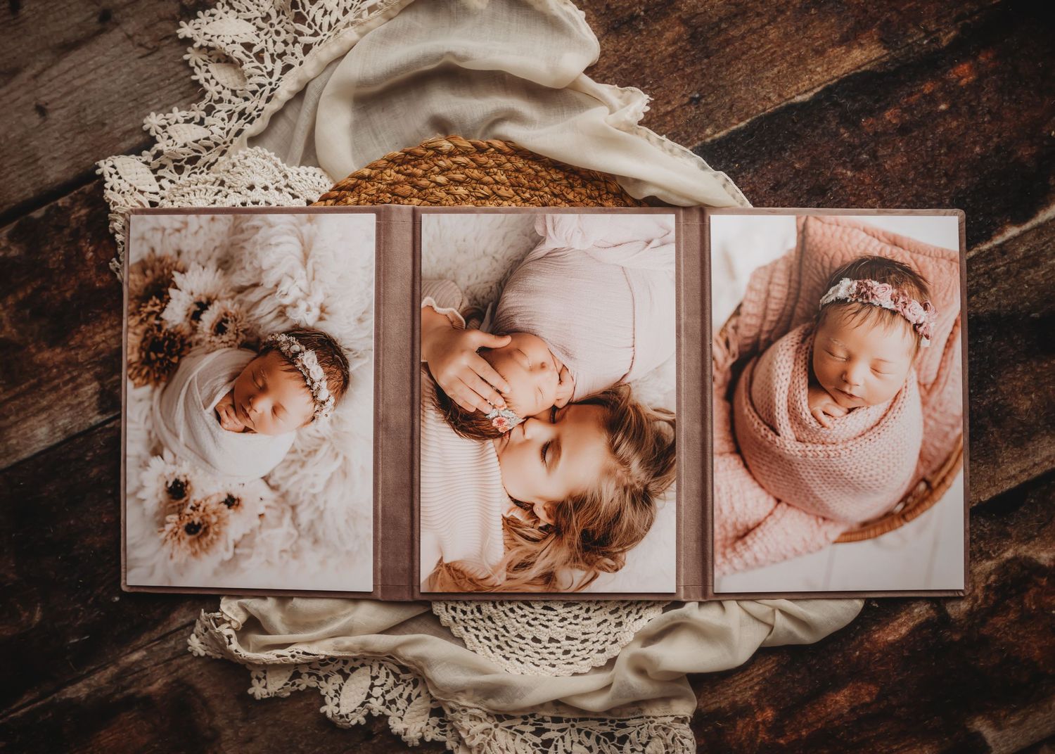 Three framed newborn photographs arranged on lace doilies and rustic wood.