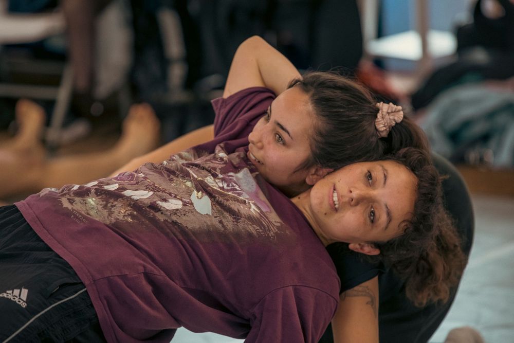 Two dancers perform an intimate contemporary dance move while lying on the studio floor.
