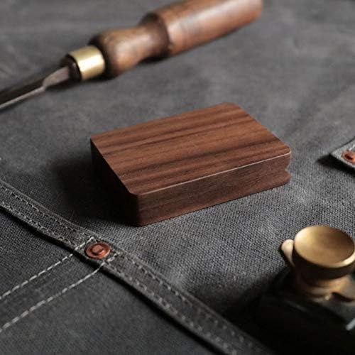 A wooden storage box sits on gray fabric next to a vintage brass pen and brass rivet detail.