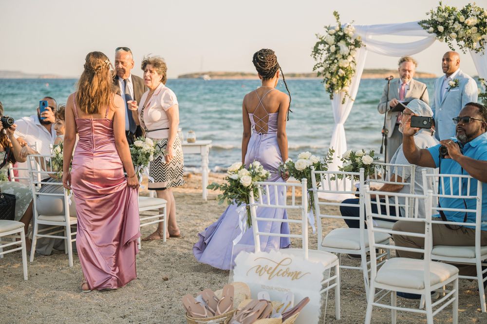 A beach wedding ceremony setup with white chairs and floral decorations against an ocean backdrop.