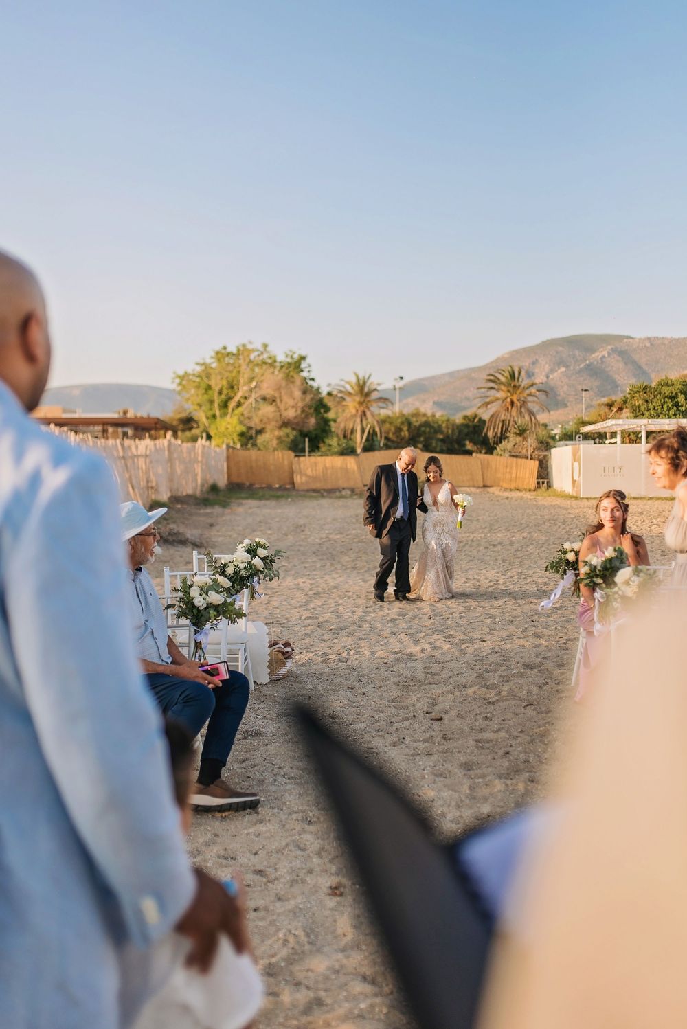 An intimate beach wedding ceremony taking place with mountains and palm trees in the background.