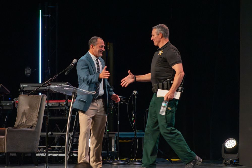 Two speakers engaging in discussion on dark stage during presentation.