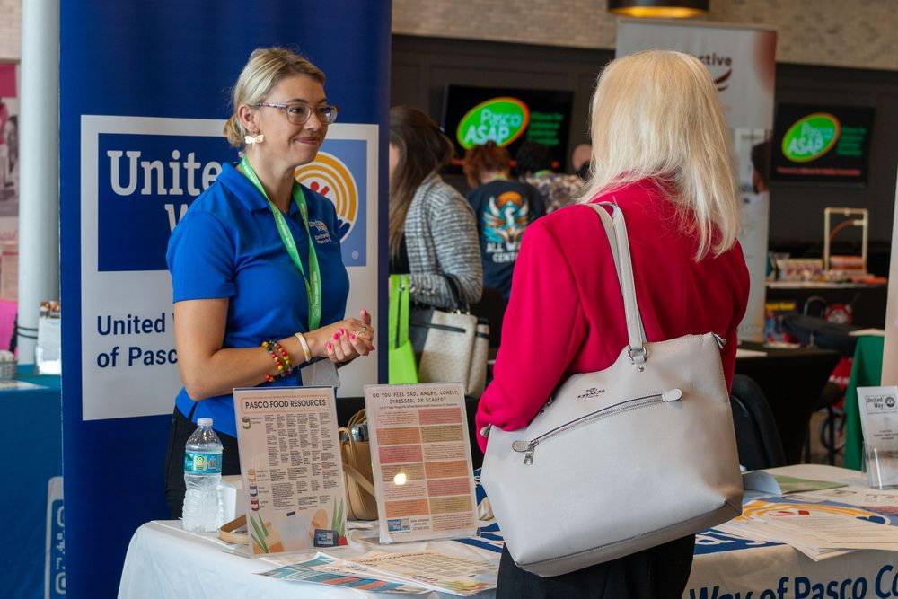 Networking event with participants at tables and organizational banners displayed.