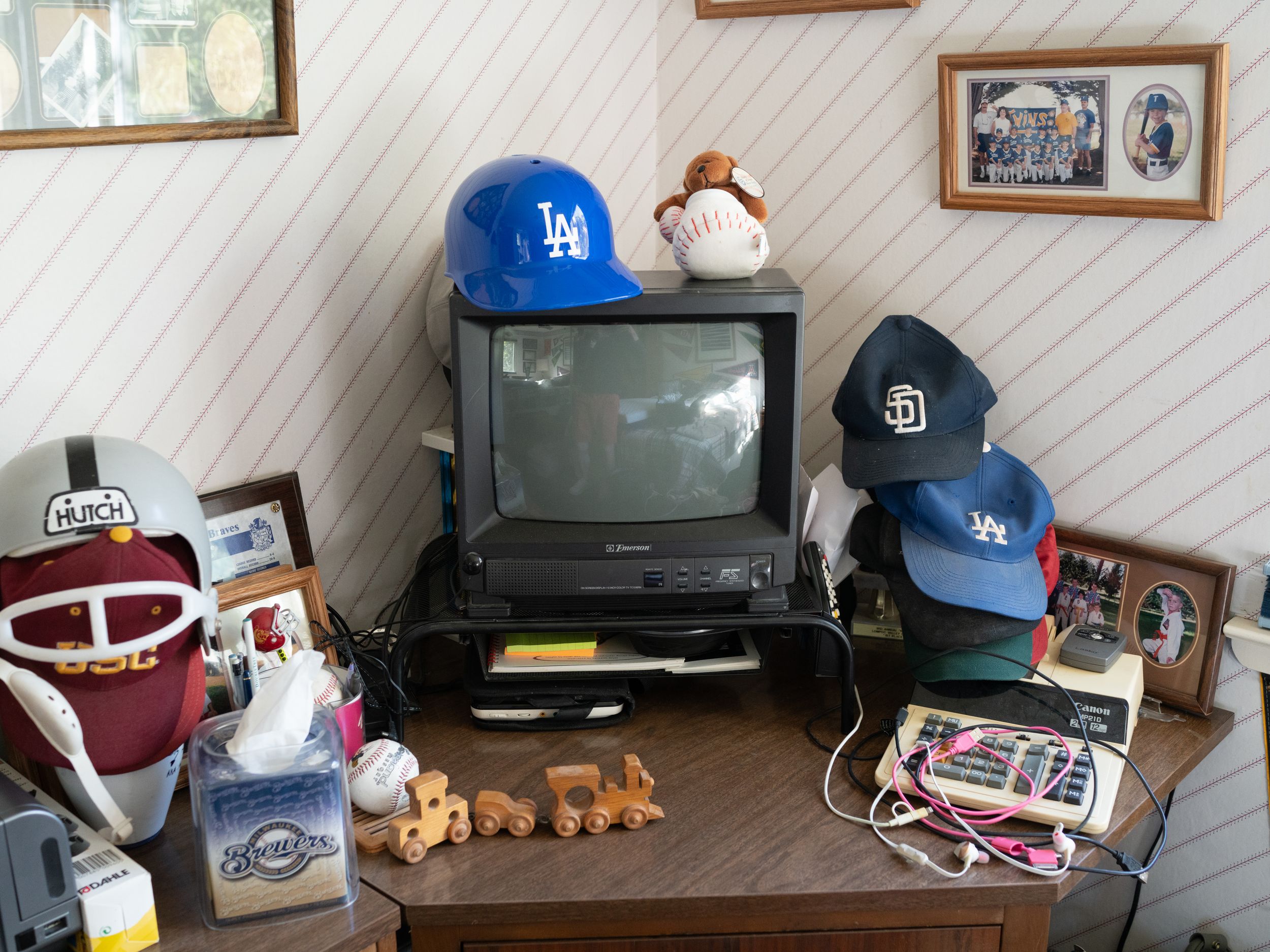 Vintage television display with baseball caps, sports memorabilia, and collectibles arranged on wooden furniture.