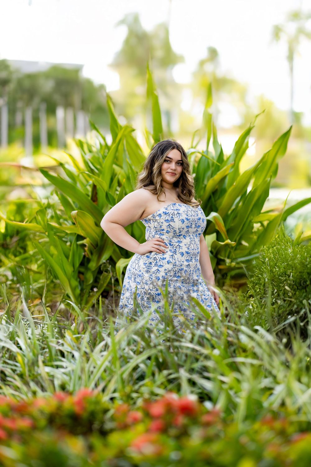 A floral dress photoshoot among lush tropical plants and red flowers.