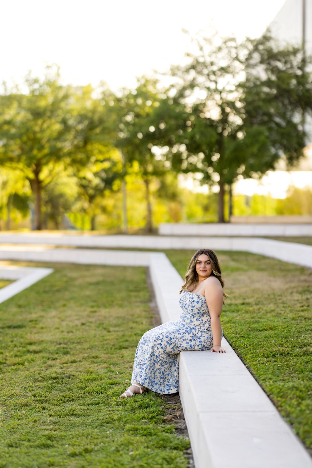 A relaxed pose on a grassy hillside wearing a floral sundress.