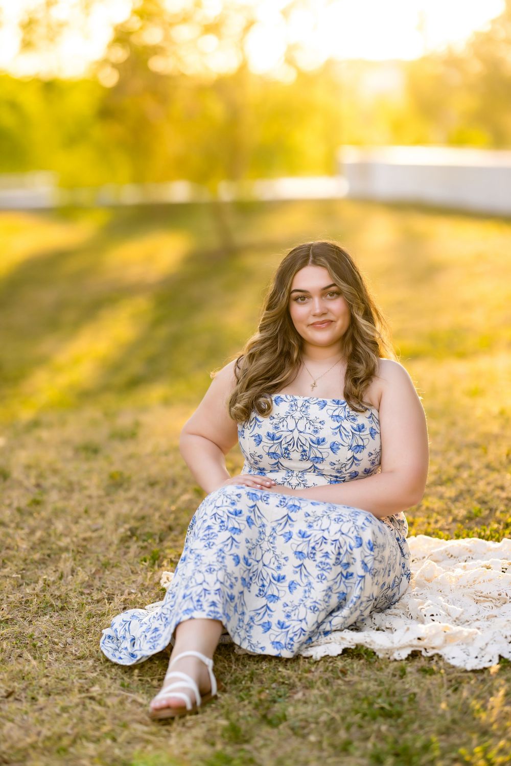 Reclining on grass during golden hour in a delicate floral dress.