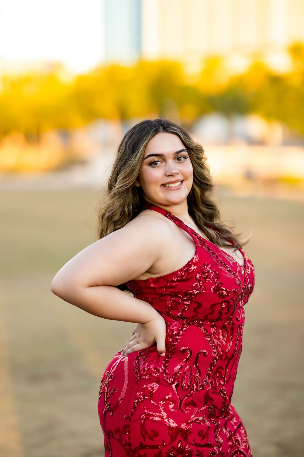 Posing in a sparkly red dress during a golden sunset photoshoot.