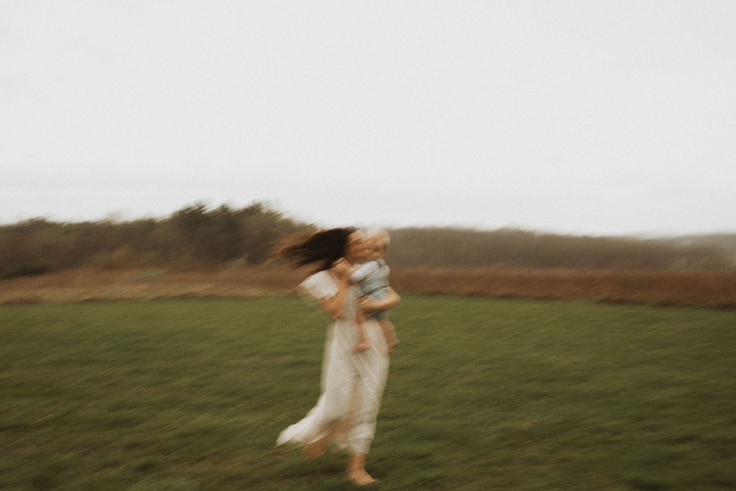 Ethereal motion-blur photo of someone dancing in a field wearing white.