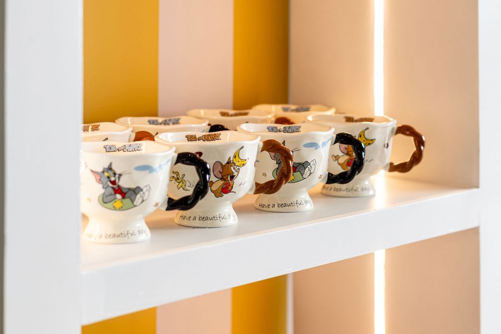 Display shelf of Tom and Jerry themed ceramic cups arranged in a row.