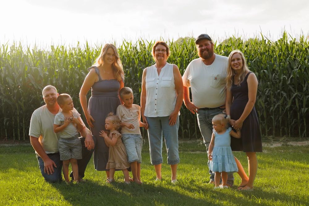 A series of outdoor family photos taken in front of a cornfield at sunset with matching casual outfits.