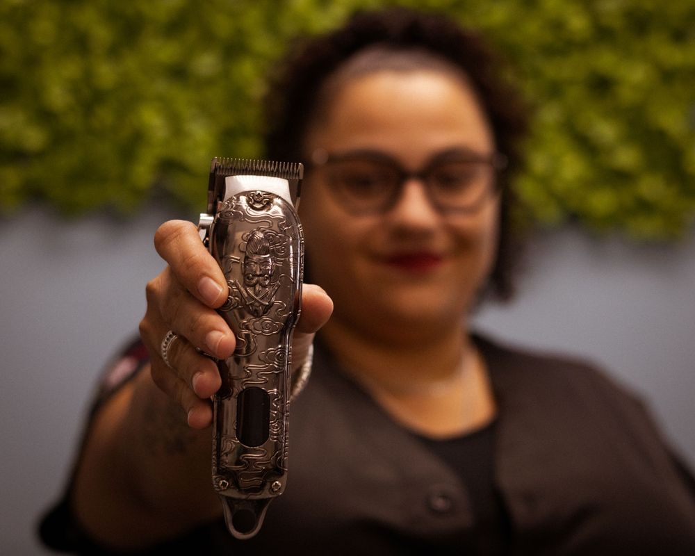 Decorative metal hair clipper being showcased against blurred background.