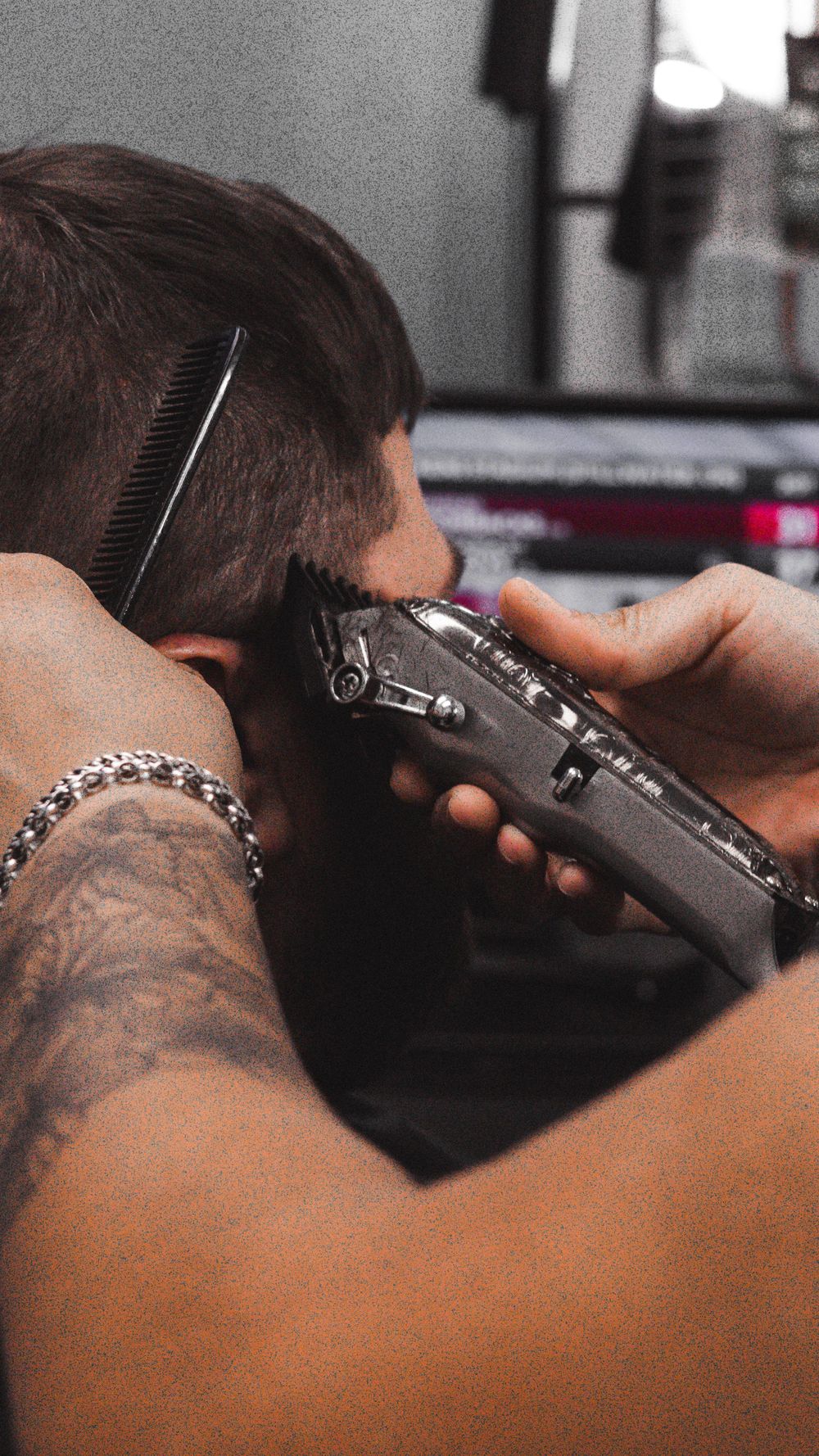 Professional barber using electric clippers for a precise haircut in a modern barbershop setting.