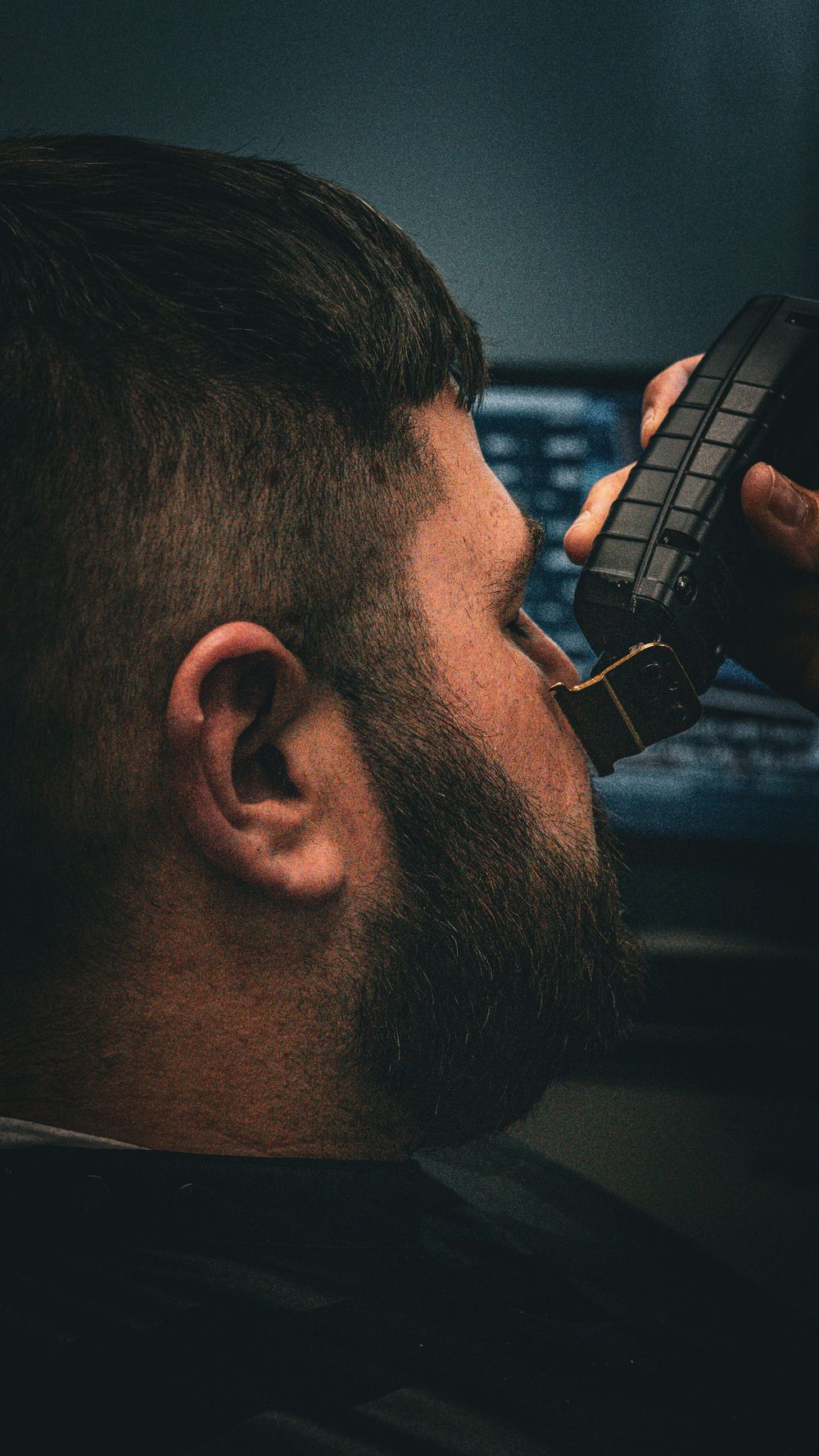 Side view of beard trimming process using professional grooming equipment.
