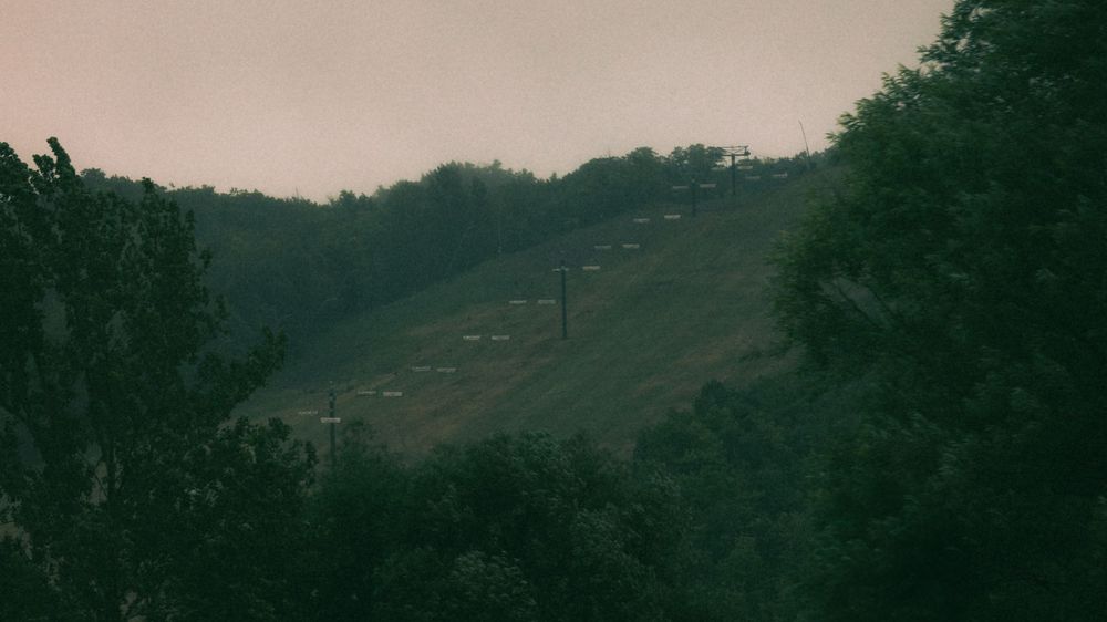 A misty mountain landscape stretches into the distance under an overcast sky.
