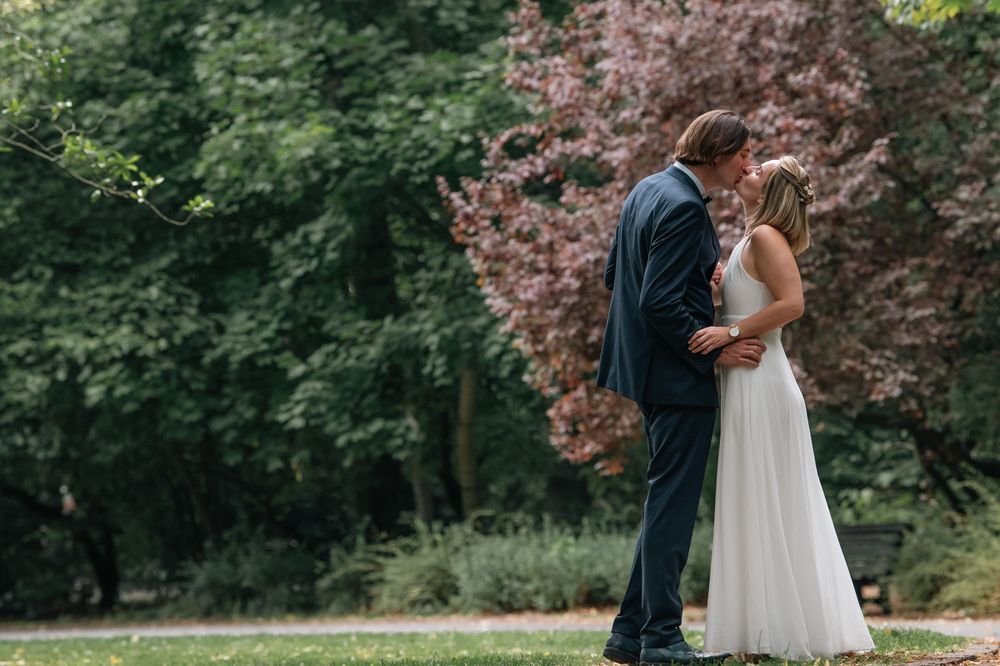 Newlyweds enjoying a romantic dance together in a park with blooming trees.