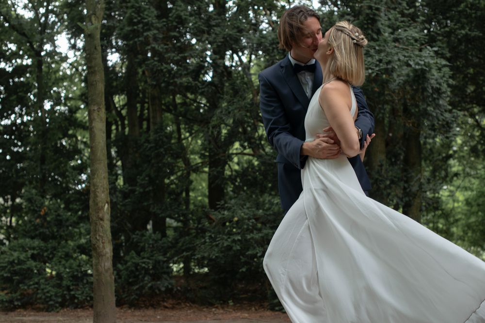 Couple dancing together surrounded by trees in an outdoor wedding celebration.