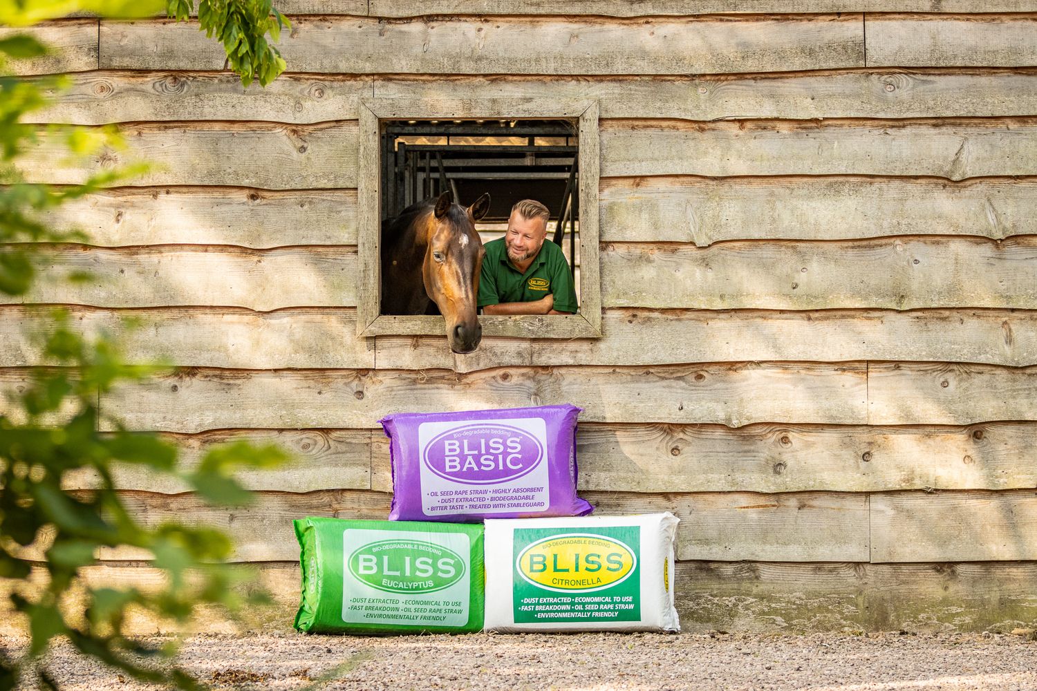 Farm scene with colorful feed bags stacked beneath a rustic wooden barn window.