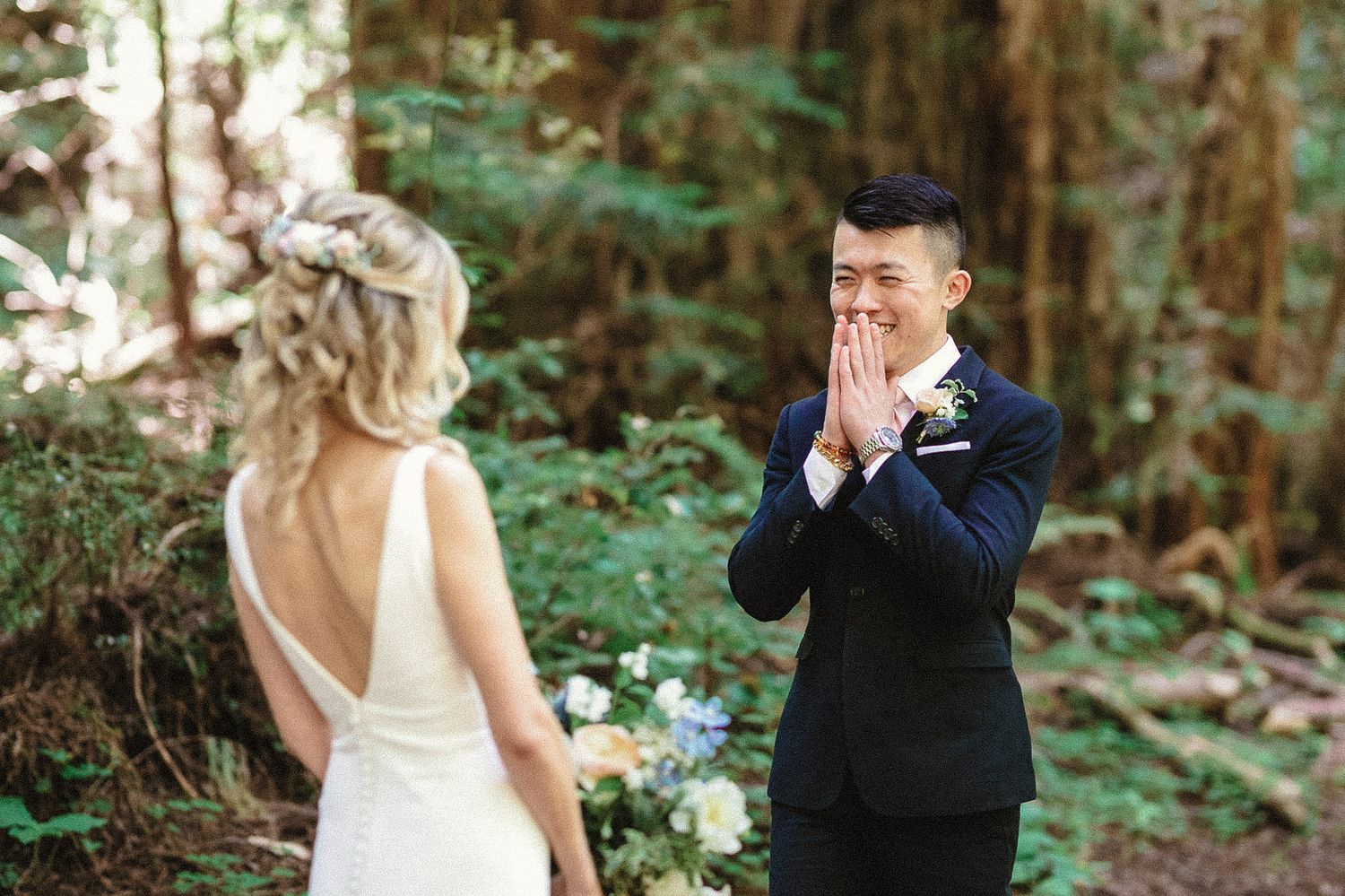 An emotional first look moment between a couple in a serene forest setting.