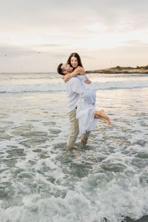A couple embraces and plays in ocean waves during golden hour at the beach. Second Beach, Newport and Middletown, RI