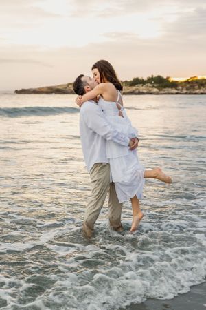 A romantic embrace in the ocean waves with coastal cliffs visible at sunset. Second Beach, Newport and Middletown, RI