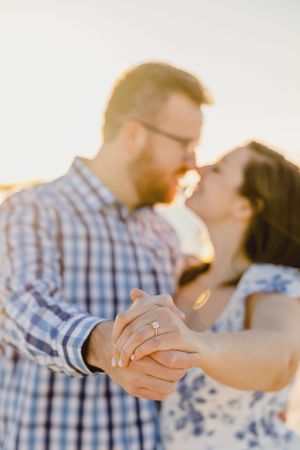 A couple dances together during golden hour, showcasing their engagement ring. Engagement Session RI