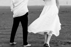 A black and white photo of two people dancing on a beach, showing their feet and flowing dress. First beach Newport, RI