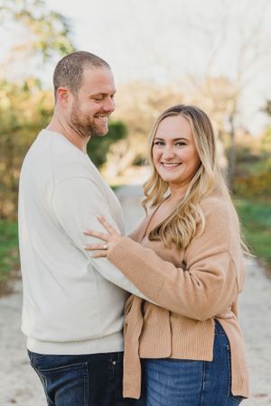 A couple embraces while wearing cozy sweaters during an autumn outdoor photoshoot. Engagement Session Newport, RI