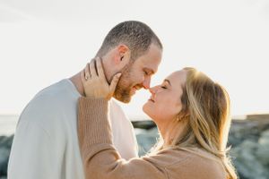 An intimate moment shared between a couple in matching neutral sweaters at the coast. Engagement Session Newport, RI